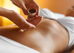 Manos vaciando aceite para masaje